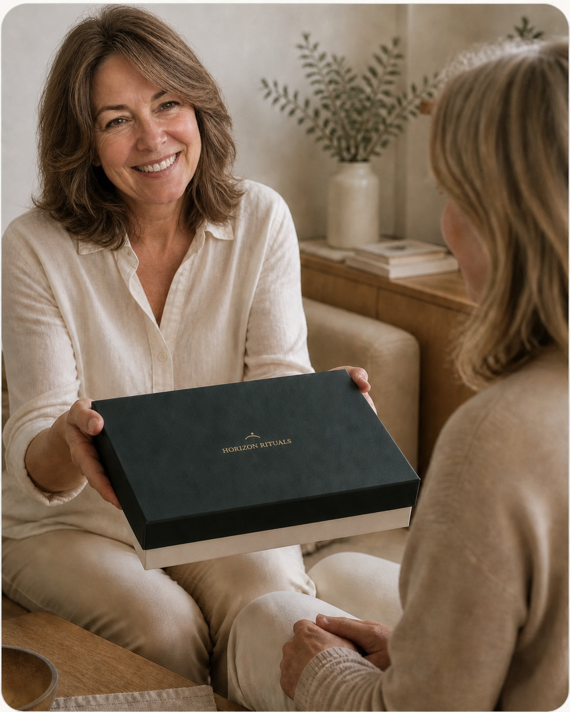 Une femme offre le Coffret Horizon fermé à une autre femme avec un geste simple et respectueux