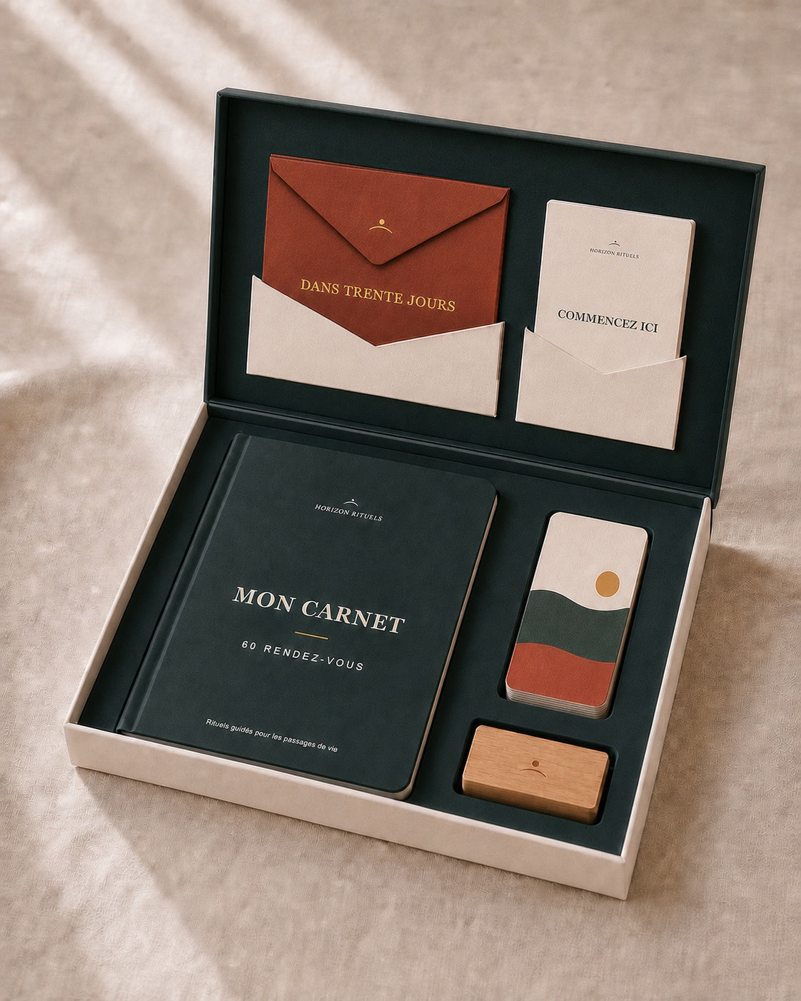 Coffret Horizon ouvert : carnet, porte-carte et pile de cartes avec sa carte d’ouverture illustrée dans un plateau unique, enveloppe terracotta et notice ivoire