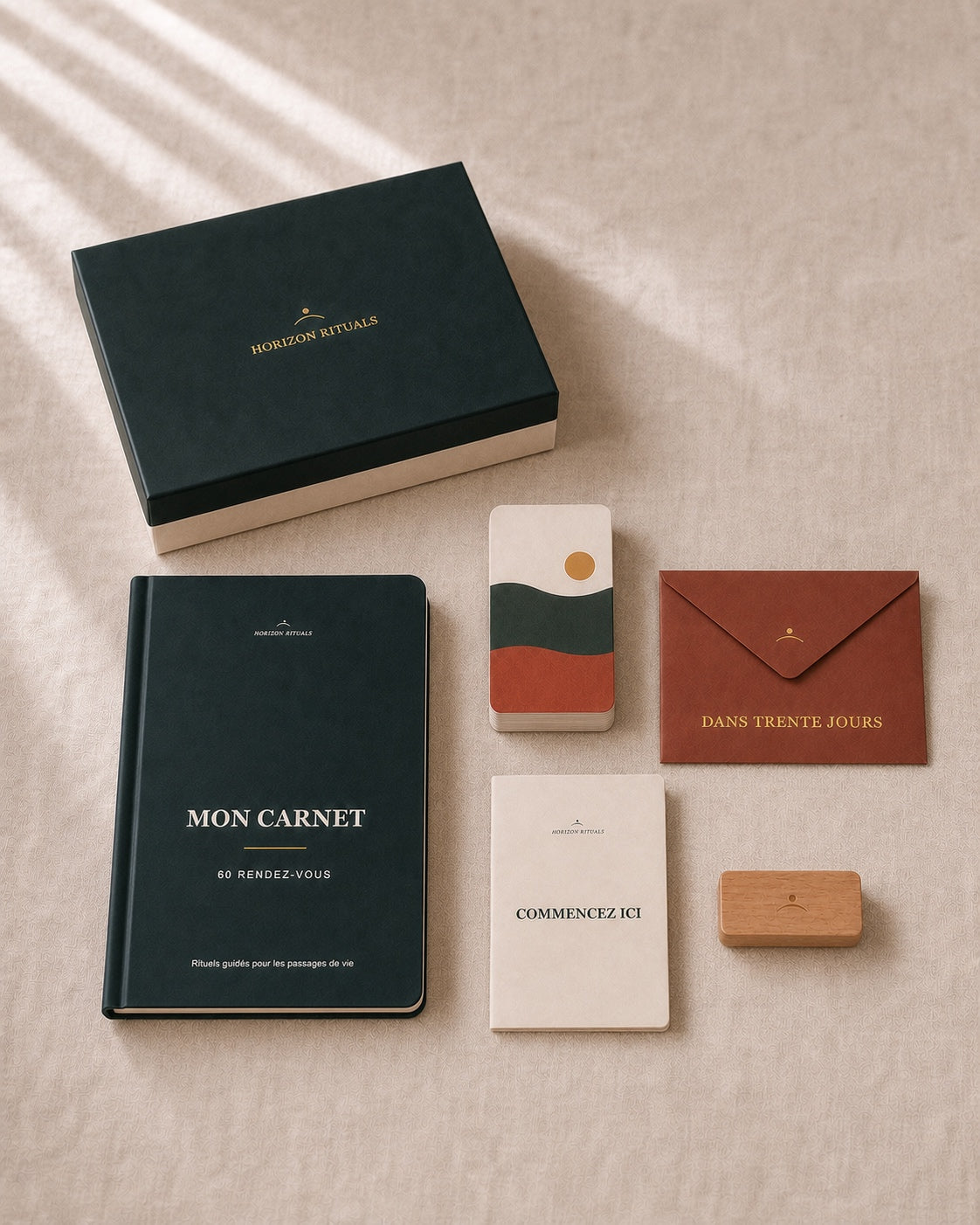 Contenu physique du coffret à l’échelle : coffret fermé, carnet guidé, pile de 70 cartes surmontée de sa carte d’ouverture illustrée, porte-carte en hêtre clair, enveloppe terracotta et notice ivoire